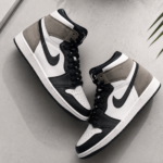 Premium Air Jordan-style sneakers arranged in a clean flat-lay on a light gray minimalist background with soft studio lighting, highlighting the leather texture, stitching, and modern high-top design in a wide commercial banner composition.
